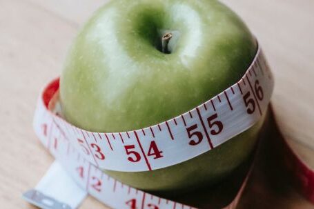 Fitness Nutrition - Green apple with measuring tape on table in kitchen