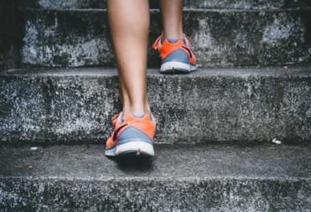 Exercise - person wearing orange and gray Nike shoes walking on gray concrete stairs