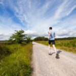 Exercise - man running on road near grass field