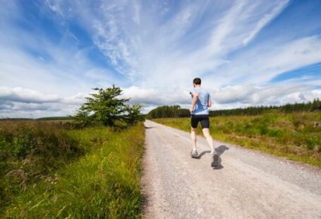 Exercise - man running on road near grass field