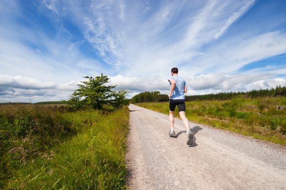 Exercise - man running on road near grass field