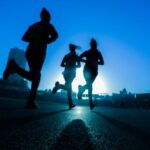 Exercise - silhouette of three women running on grey concrete road