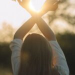 Stretching Integration - Young Woman Standing on the Meadow Stretching Her Arms Towards Rising Sun