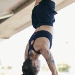 Fitness Progress - A Woman in Black Shorts and Sports Bra Doing Hand Stand while Holding on Metal Bars