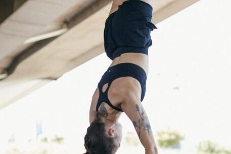 Fitness Progress - A Woman in Black Shorts and Sports Bra Doing Hand Stand while Holding on Metal Bars