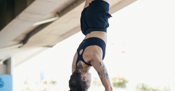 Fitness Progress - A Woman in Black Shorts and Sports Bra Doing Hand Stand while Holding on Metal Bars