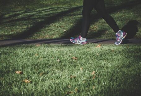 Exercise - shallow focus photography of person walking on road between grass